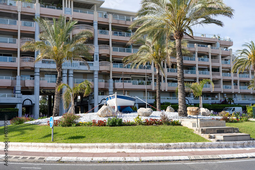 A roundabout with a fishing boat in front of a large residence in the city center of Golf-Juan in southern France.