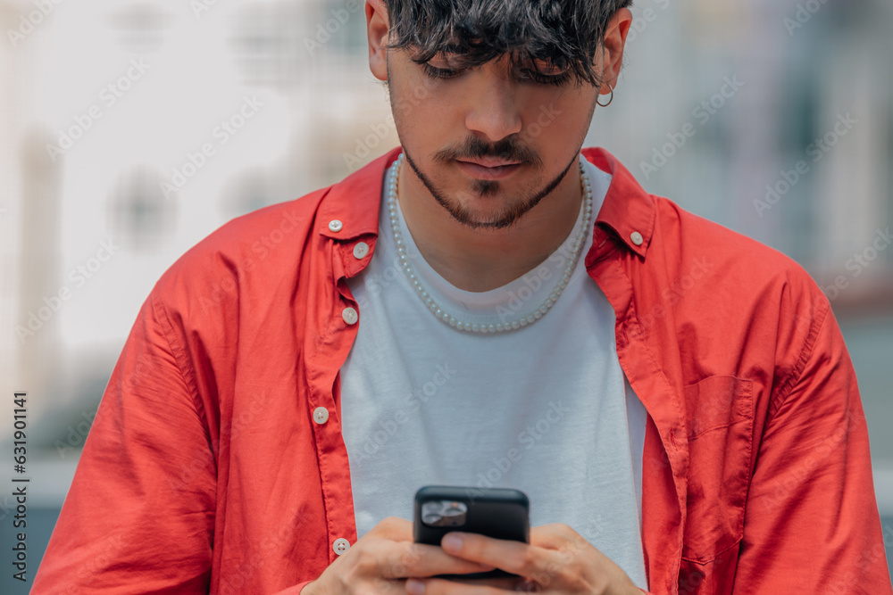 Fototapeta premium young man on the street looking at the mobile phone