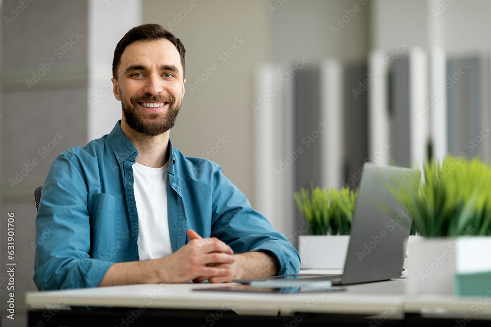 Portrait of freelancer man sitting at desk with laptop computer at office Portrait of freelancer man sitting at desk with laptop computer at office