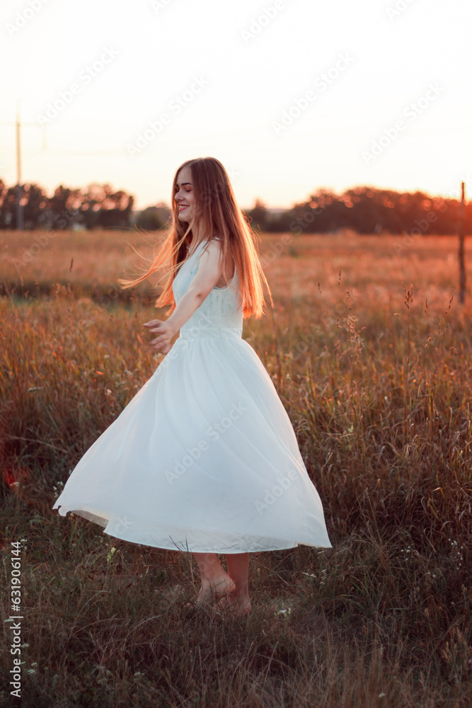 A beautiful pretty girl is dancing on a field at sunset in a white dress. Happy woman. Concept. Bride A beautiful pretty girl is dancing on a field at sunset in a white dress. Happy woman. Concept. Bride