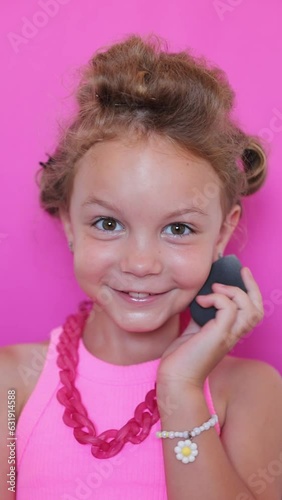 cute girl make-up on camera, in pink clothes on pink background, little blogger and makeup artist, vertical video