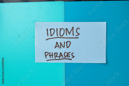 Concept of Idioms and Phrases write on sticky notes isolated on Wooden Table.