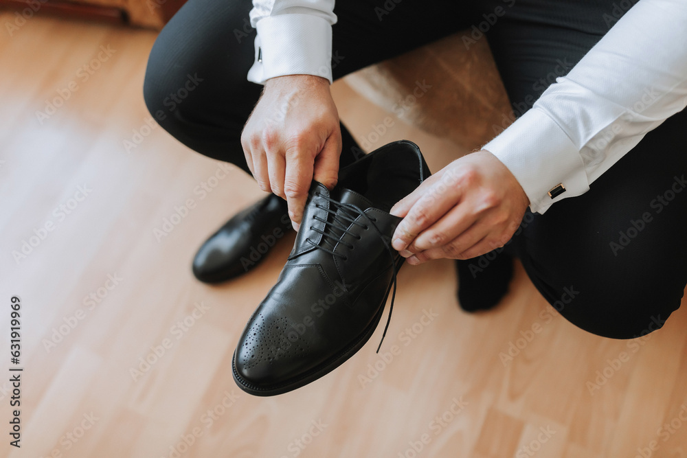 A stylish groom is preparing for the wedding ceremony. Groom's morning. The businessman wears black shoes. The groom is getting ready in the morning before the wedding ceremony