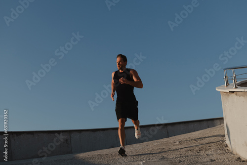 Handsome young man in sports clothing enjoying morning jog outdoors