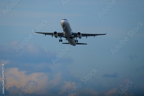  An airlane taking off from the runway against a bright cloudy sky.
