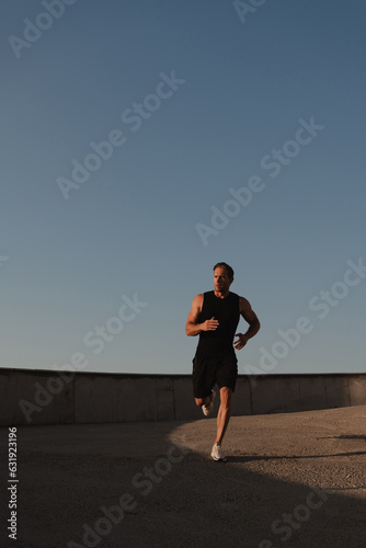 Athletic young man in sports clothing enjoying morning jog outdoors
