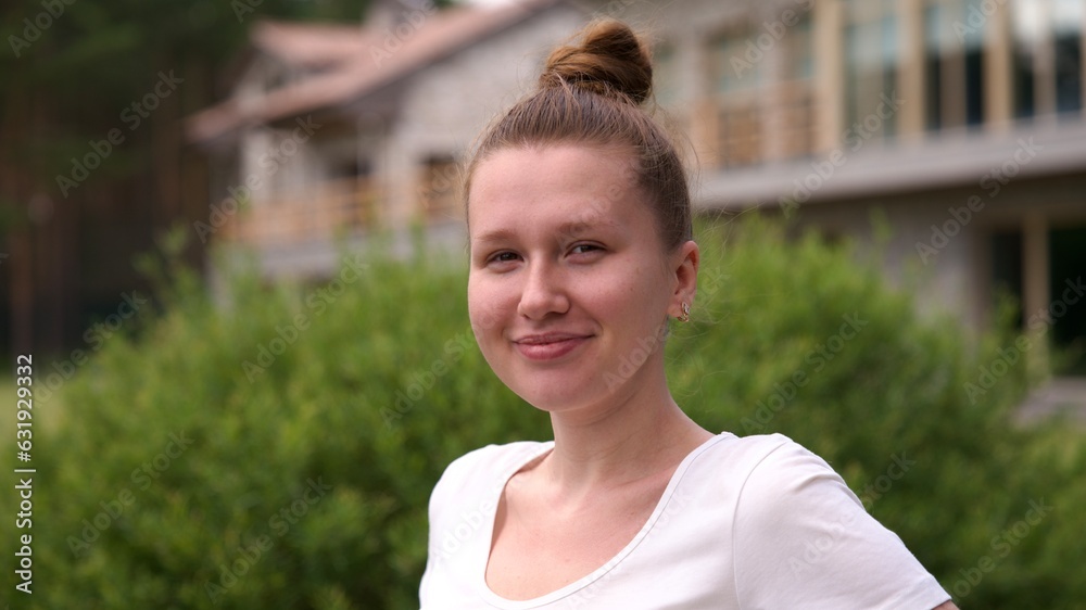 Portrait of happy young woman standing in the garden outside her luxury home and smiling and relax outside 