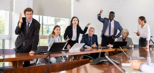 Multiracial group of age-diverse business people in formalwear having an emotional dispute and verbal altercation during corporate group meeting in conference room at office finding no compromise in
