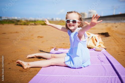 Adorable preshooler girl playing on the sand beach at Atlantic coast of Brittany, France photo