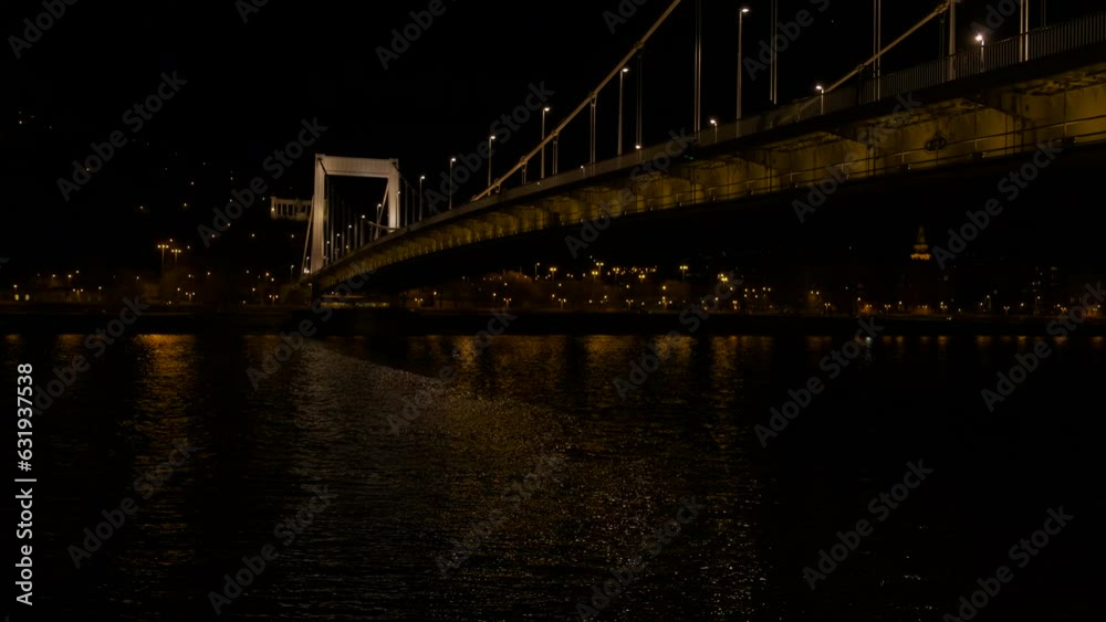 Night traveling on danube under bridge. A cute night traveling on Danube river against bright chained bridge. Night traveling on danube under bridge. A cute night traveling on Danube river against bright chained bridge.