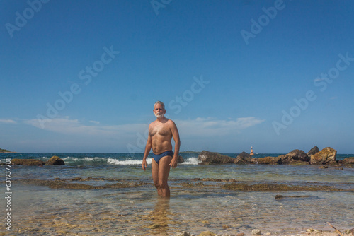 Fototapeta mature man in the tropical beach with blue speedo