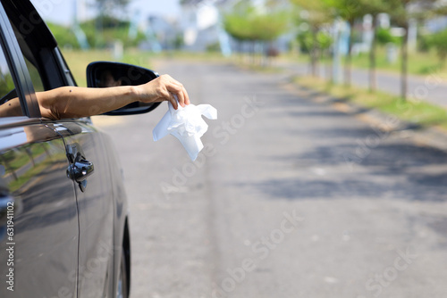 female driver's hand throwing tissue waste on the road