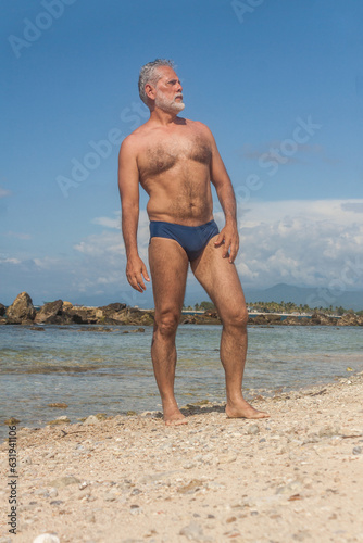 mature man in the tropical beach with blue speedo photo