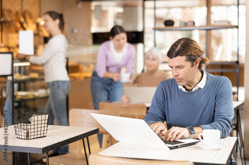 Confident male cafe customer enjoying peace and quiet while working on laptop