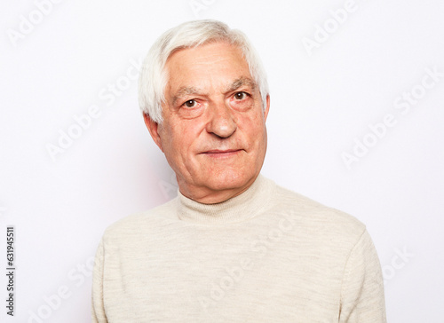Senior man with gray hair frowns and looks displeased over white background. © Raisa Kanareva