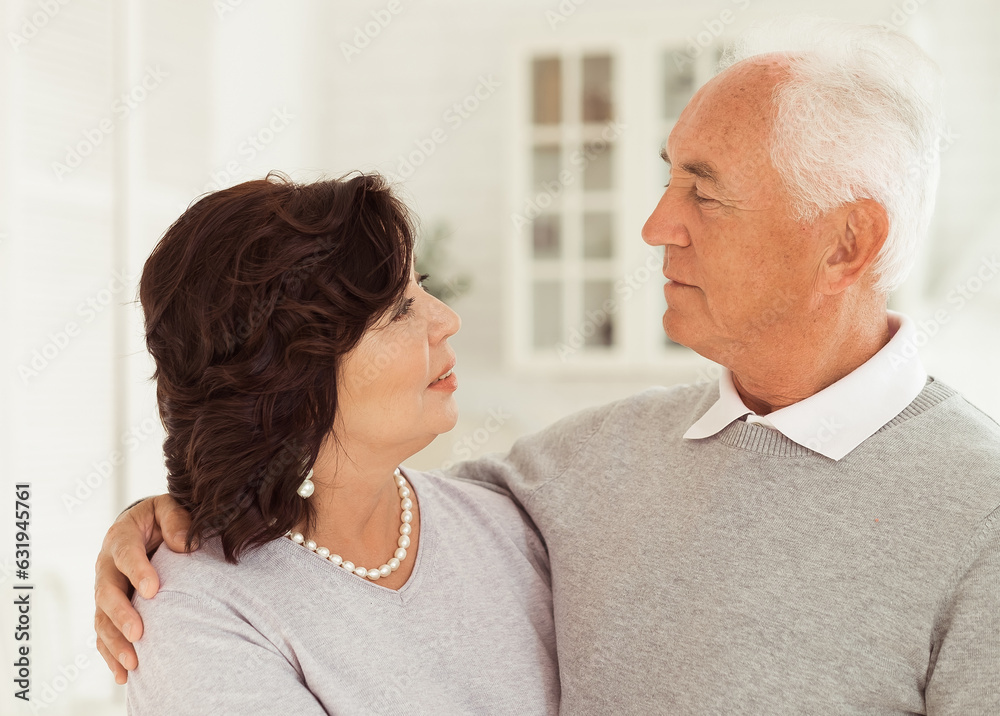Portrait of cute happy Caucasian couple of retired husband and wife hugging indoors.