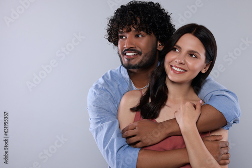 International dating. Happy couple hugging on light grey background, space for text