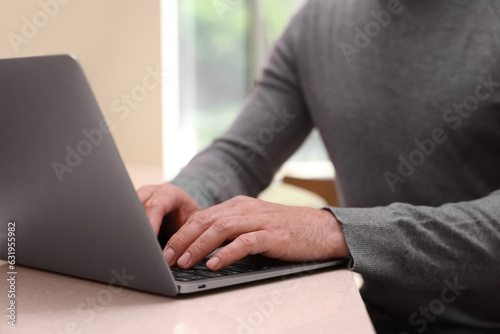 Man working on laptop at table in cafe, closeup