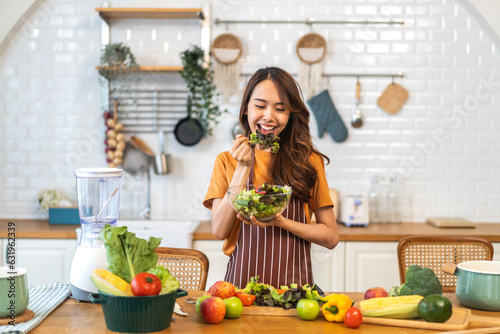 Portrait of beauty body slim healthy asian woman eating vegan food healthy with fresh vegetable salad in kitchen at home.diet  vegetarian  fruit  wellness  health  green food.Fitness and healthy food