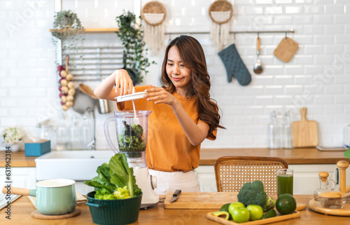 Portrait of beauty healthy asian woman making green vegetables detox cleanse and green fruit smoothie with blender.young girl drinking glass of green fruit smoothie in kitchen.Diet.healthy drink