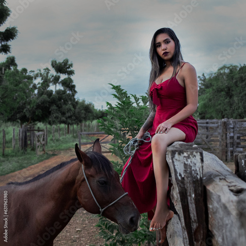 Camponesa de vestido longo vermelho com cavalo castanho.