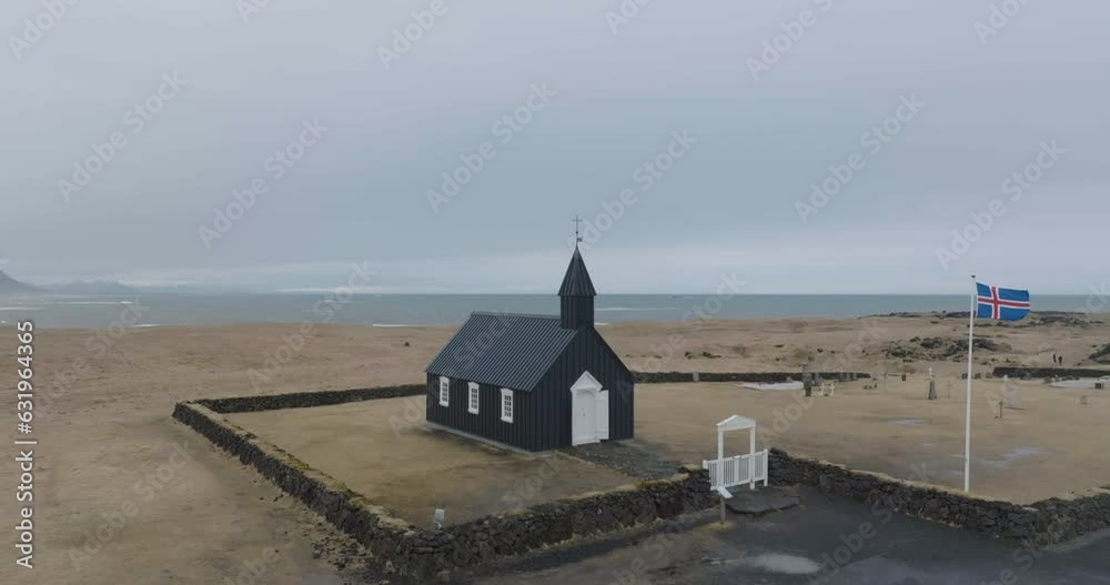 Drone Shot of Church in Búðir, Iceland, Black Wooden Building and National Flag by the Sea Drone Shot of Church in Búðir, Iceland, Black Wooden Building and National Flag by the Sea