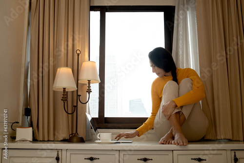 woman working from home Use a computer to sit by the window working on online project, searching information