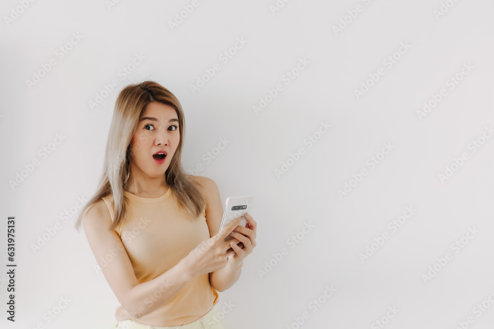 Shocked and surprised face of asian woman in yellow top using smartphone isolated on white. Shocked and surprised face of asian woman in yellow top using smartphone isolated on white.