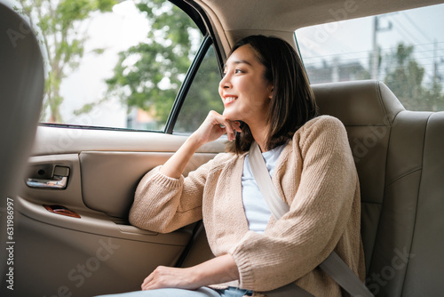 Tableau sur toile Relaxing moment of beautiful woman sitting in car back seats with safety belt and look out in the window