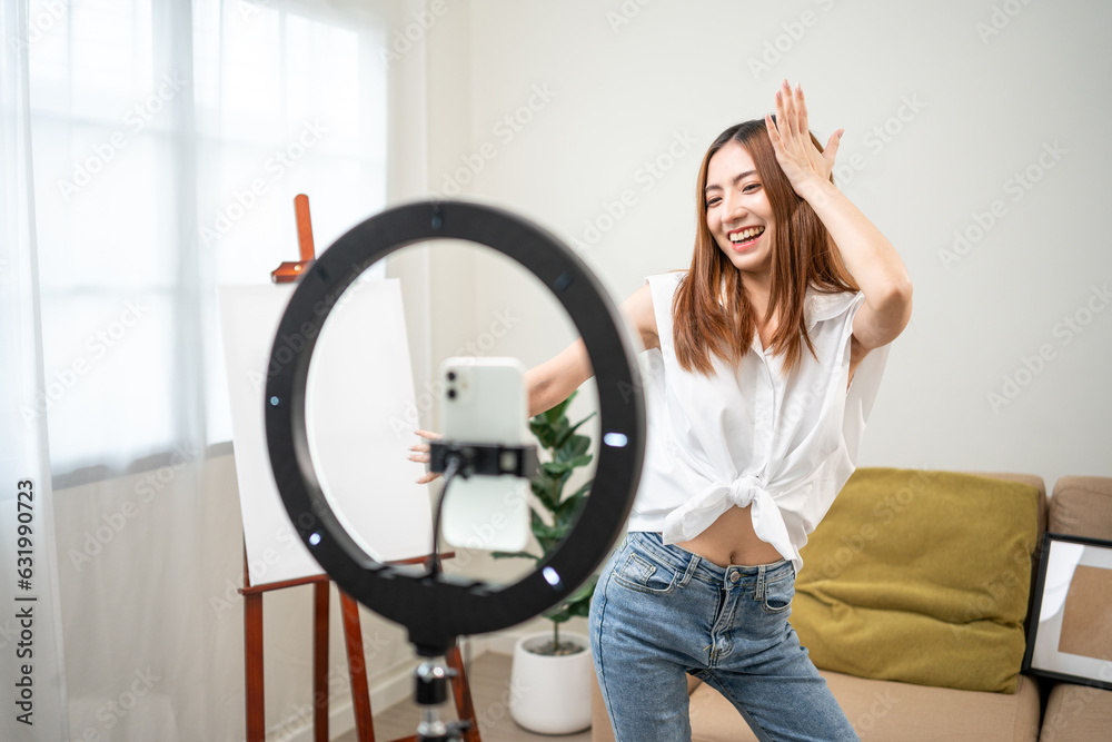 Young trendy influencer asian woman dancing on mobile phone at home in living room. Creator vlogger talent dancing enjoy hobby content recording show video sharing on social media. Young trendy influencer asian woman dancing on mobile phone at home in living room. Creator vlogger talent dancing enjoy hobby content recording show video sharing on social media.