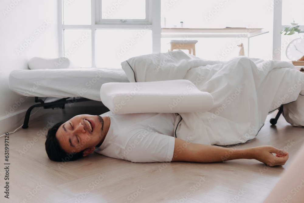 Asian man falling down from the bed lying on the floor at home. Asian man falling down from the bed lying on the floor at home.