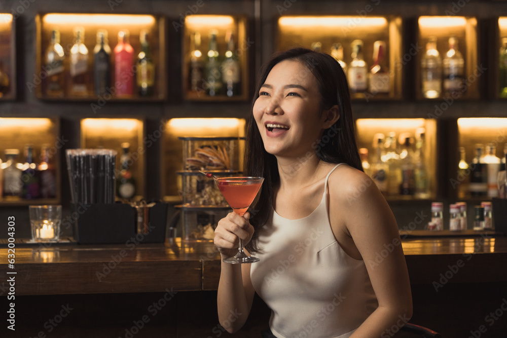 Asian woman drinking a cocktail at a bar at night. Asian woman drinking a cocktail at a bar at night.