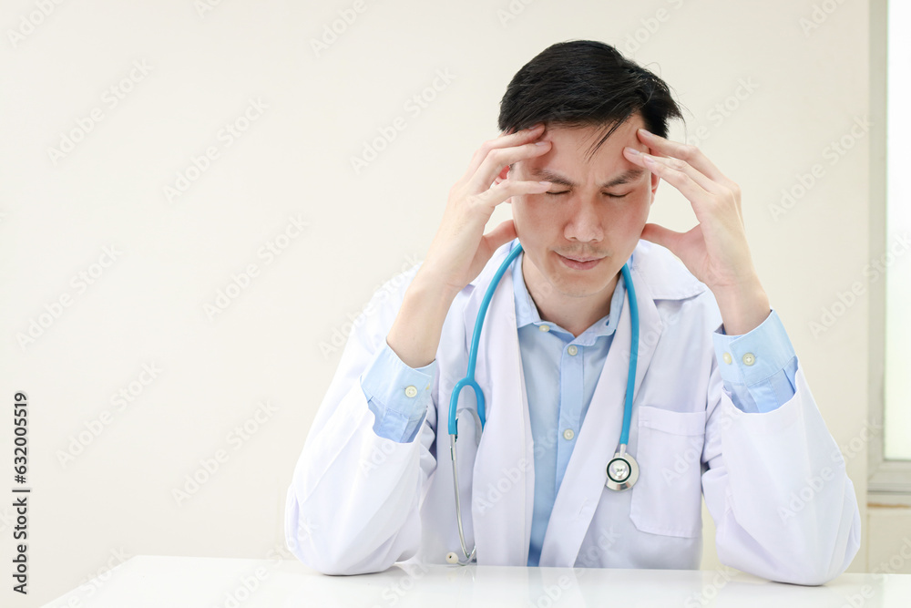 Portrait of a stressed Asian male doctor sitting at his desk. Depression in medicine, reduce stress. health concept. Portrait of a stressed Asian male doctor sitting at his desk. Depression in medicine, reduce stress. health concept.