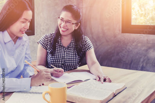 Two chrsitian woman enjoying study bible together with open bible and a cup of coffee on wooden table with copy space photo