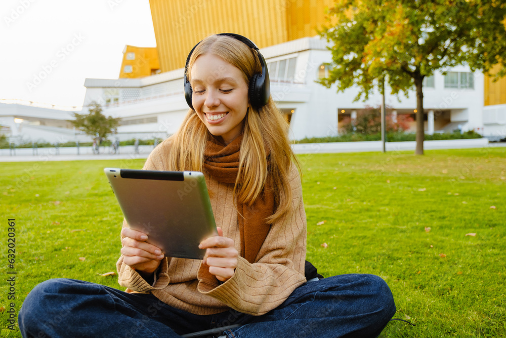 Obraz premium Cheerful woman using tablet while sitting in park