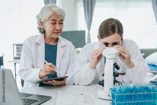 Scientists are doing research in a medical laboratory. Foreground researcher using a microscope