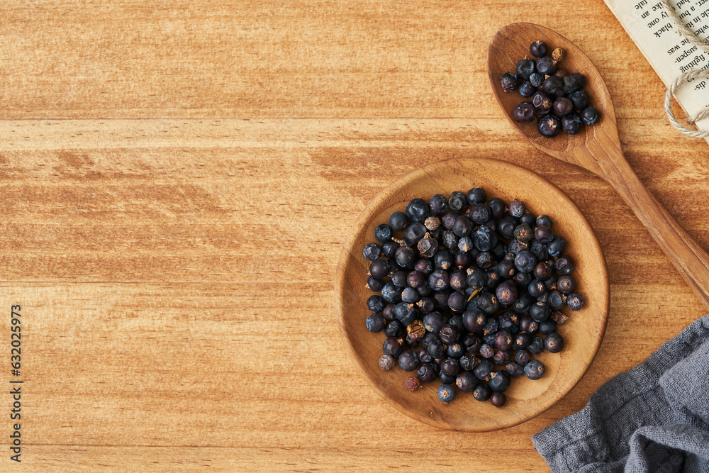 top view flat lay overhead dry juniper berry seed in wood plate on wooden table background. dry juniper berry seed background. heap of dry juniper berry seed food background top view flat lay overhead dry juniper berry seed in wood plate on wooden table background. dry juniper berry seed background. heap of dry juniper berry seed food background