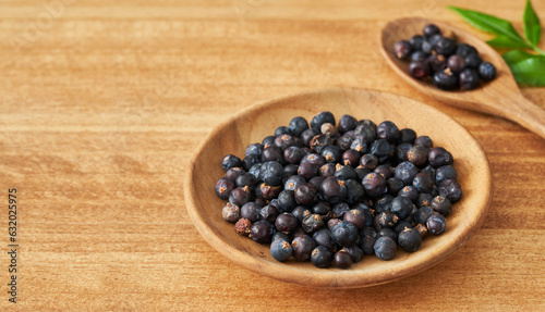 dry juniper berry seed in wood plate on wooden table background. dry juniper berry seed background. heap of dry juniper berry seed food background                          