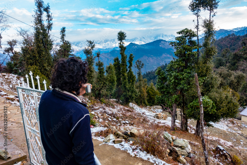 Tourist sipping tea, admiring snow-capped Himalayas in Garhwal, Uttarakhand, India. Serene mountain view