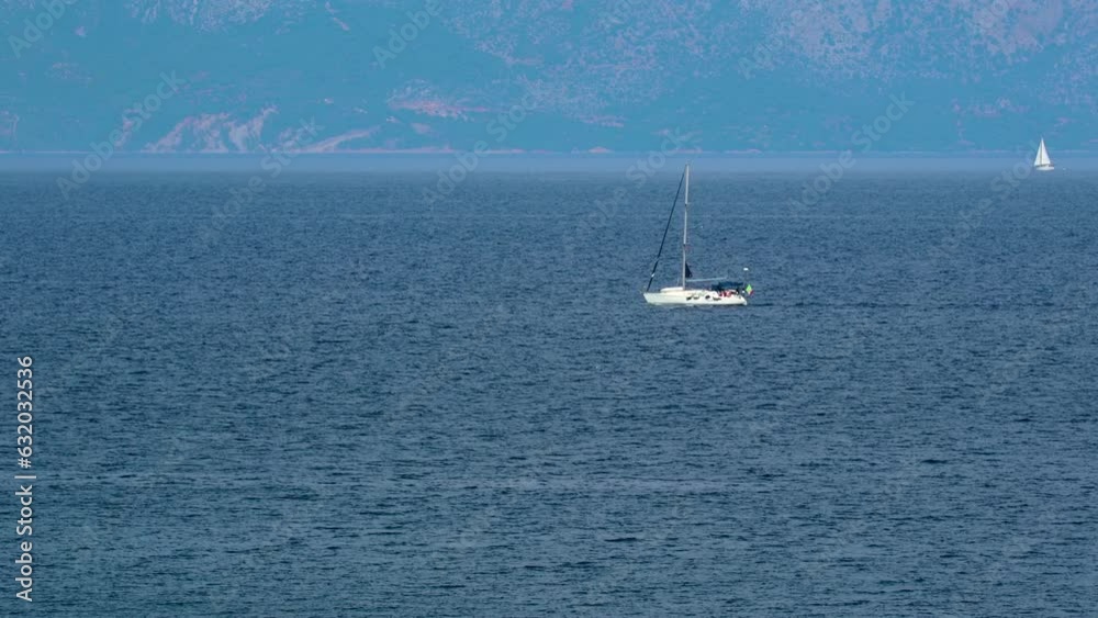 Sailing yacht navigating in blue sea water in the day time. Side view of sailing boat passing trough the frame Sailing yacht navigating in blue sea water in the day time. Side view of sailing boat passing trough the frame