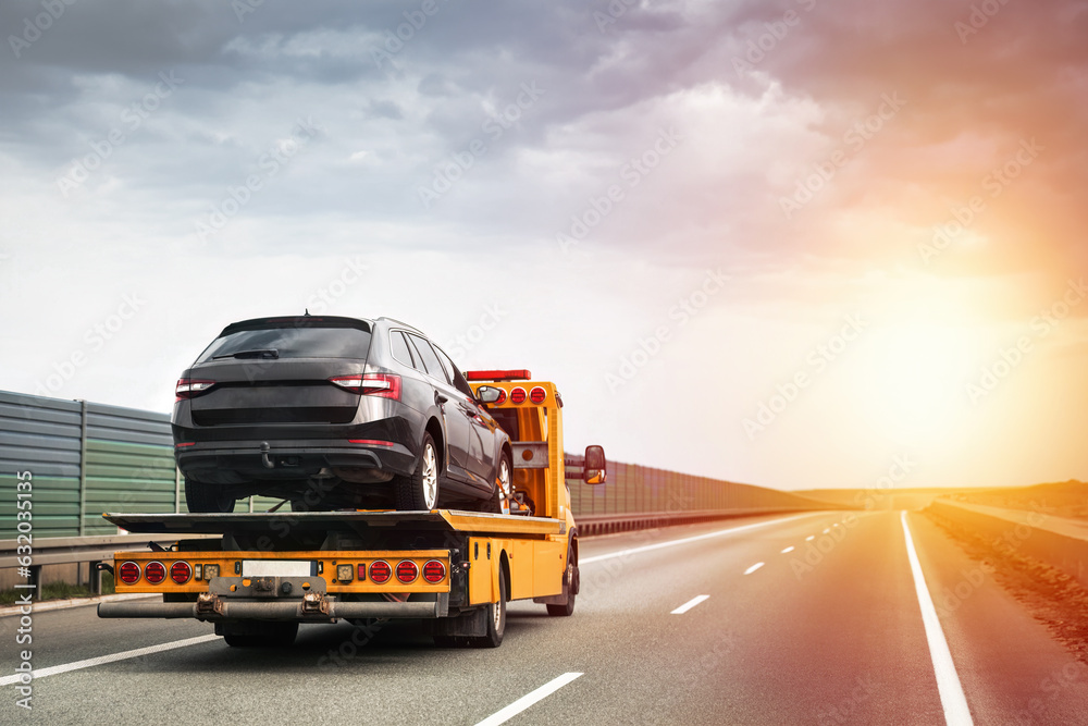 Reliable Towing and Recovery Services: 24/7 Assistance for Vehicle Breakdowns and Accidents. Emergency roadside assistance on the highway. side view of the flatbed tow truck with a damaged vehicle