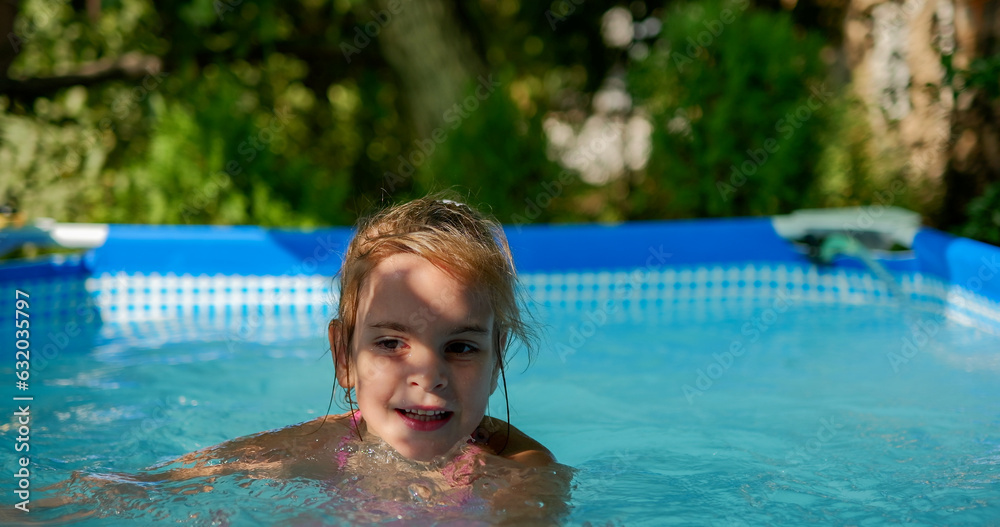 Little girl having fun with toys in the garden swimming pool.