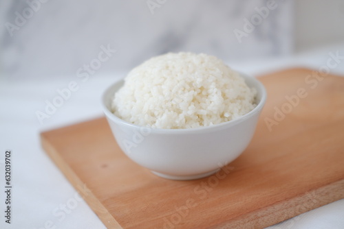 Cooked rice in a white bowl on a wooden board. Selective focus.