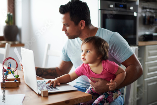 Father with baby girl using laptop on table at home photo