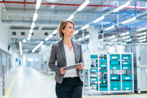 Smiling businesswoman with tablet in a modern factory photo