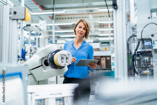 Businesswoman with tablet at assembly robot in a factory photo
