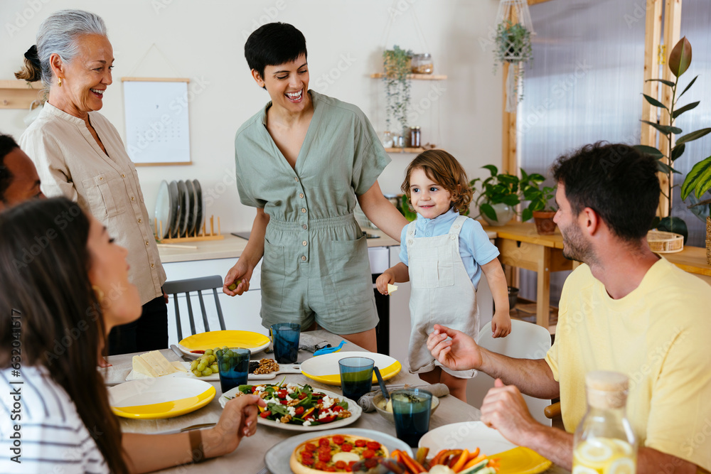 Smiling family talking to boy near dining table at kitchen Smiling family talking to boy near dining table at kitchen