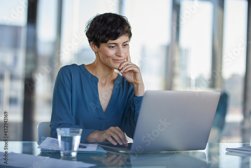 Businesswoman sitting at desk in office using laptop