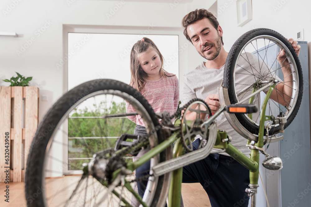 Young man and little girl repairing bicycle together Young man and little girl repairing bicycle together