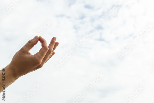 Om sign, hand on natural sky background